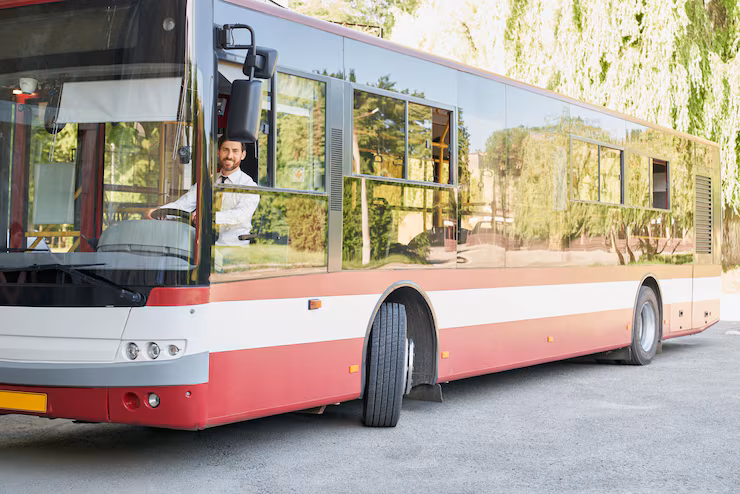 Elegant driver sitting in shuttle bus smiling to camera at summer day front view of happy man