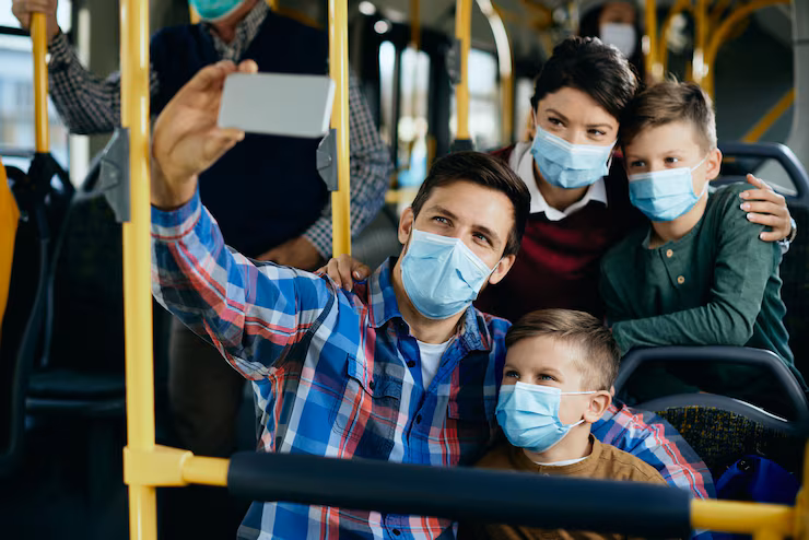 Happy family with face masks taking selfie while commuting by bus