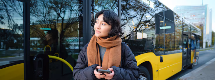 Portrait of korean girl buying ticket for public transport online using mobile application on bus