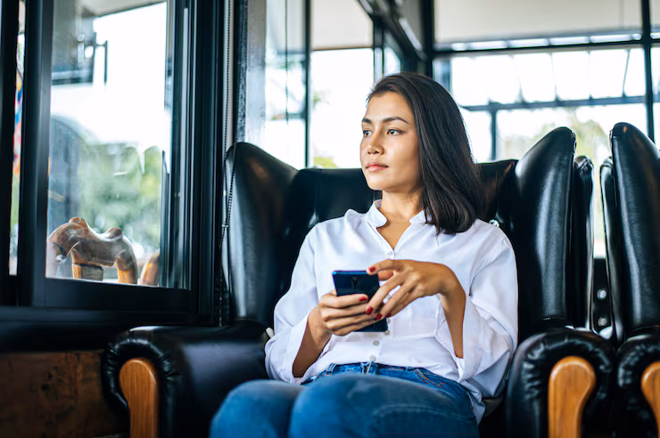 Woman looking out the window with smartphone in her hand