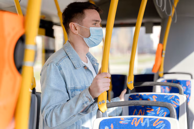 Young man travelling by city bus wearing surgical mask